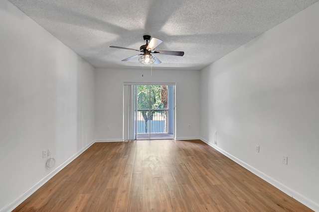 unfurnished room featuring ceiling fan, wood finished floors, a textured ceiling, and baseboards