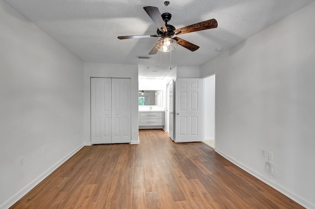 unfurnished bedroom with wood finished floors, baseboards, a textured ceiling, a closet, and a ceiling fan