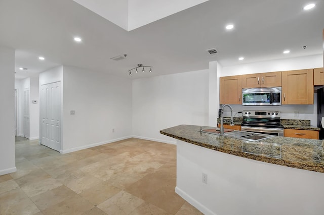 kitchen featuring stainless steel appliances, a sink, recessed lighting, dark stone countertops, and baseboards