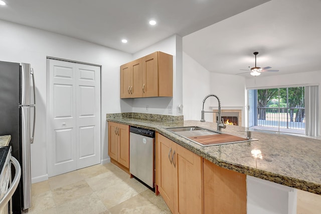 kitchen with stainless steel appliances, a sink, a lit fireplace, ceiling fan, and recessed lighting