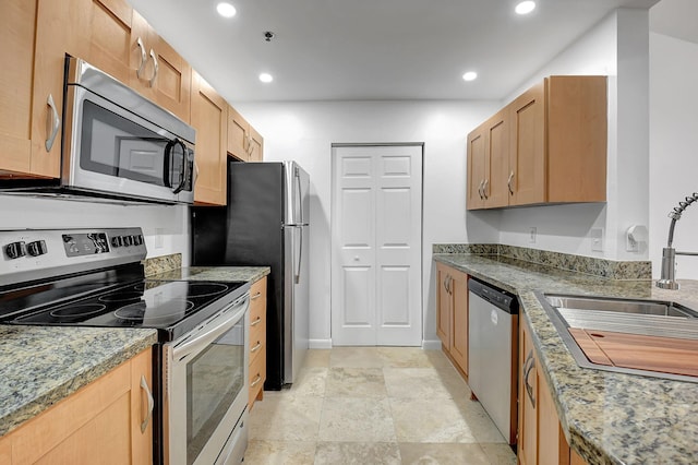 kitchen with appliances with stainless steel finishes, a sink, recessed lighting, and light stone countertops