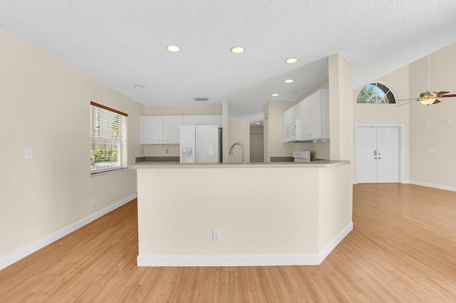 8074 Stirrup Cay Ct, Boynton Beach, FL 33436 - kitchen with white appliances, light wood-style flooring, white cabinetry, a peninsula, and a textured ceiling