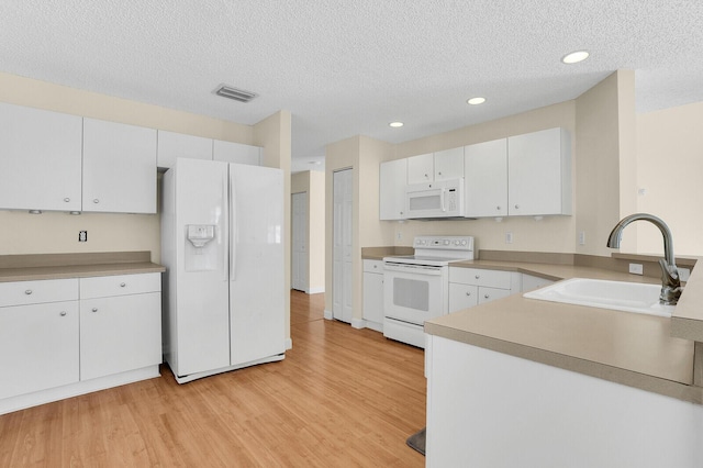 8074 Stirrup Cay Ct, Boynton Beach, FL 33436 - kitchen featuring white appliances, a sink, light wood-style floors, white cabinetry, and a textured ceiling