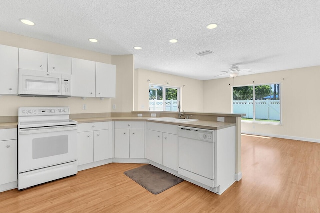 8074 Stirrup Cay Ct, Boynton Beach, FL 33436 - kitchen with white appliances, a sink, a peninsula, light wood-style flooring, and a textured ceiling