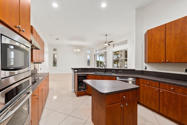 kitchen featuring appliances with stainless steel finishes, a sink, wine cooler, a center island, and dark countertops