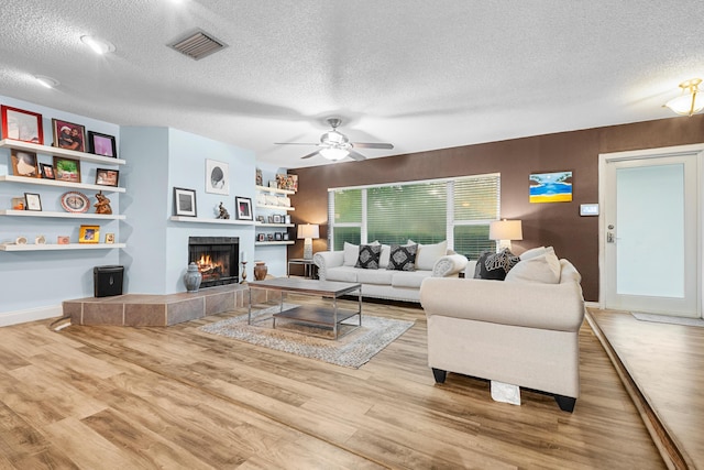 7503 NW 42nd St, Coral Springs, FL 33065 - living room with a textured ceiling, wood finished floors, a tile fireplace, ceiling fan, and baseboards