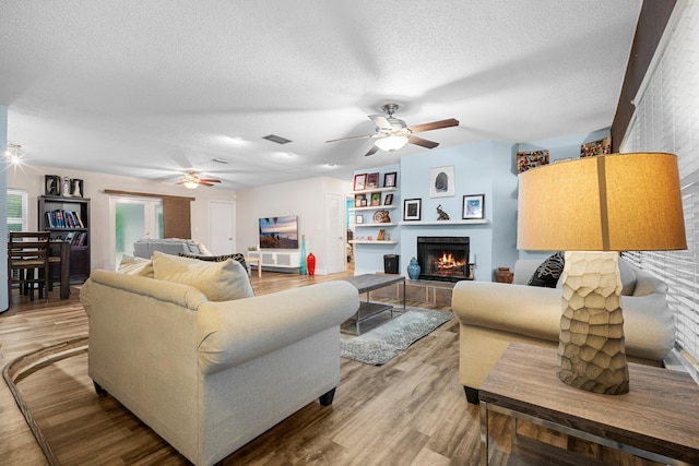 7503 NW 42nd St, Coral Springs, FL 33065 - living area featuring ceiling fan, a textured ceiling, light wood-type flooring, and a tiled fireplace
