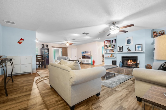 7503 NW 42nd St, Coral Springs, FL 33065 - living area with a ceiling fan, a textured ceiling, wood finished floors, and a fireplace