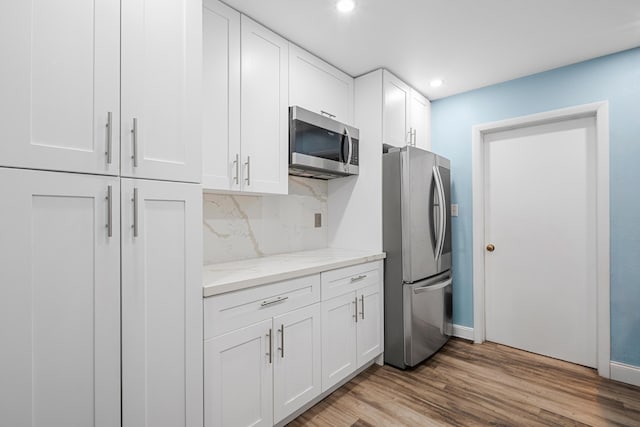 7503 NW 42nd St, Coral Springs, FL 33065 - kitchen with appliances with stainless steel finishes, decorative backsplash, white cabinets, light wood-style flooring, and recessed lighting