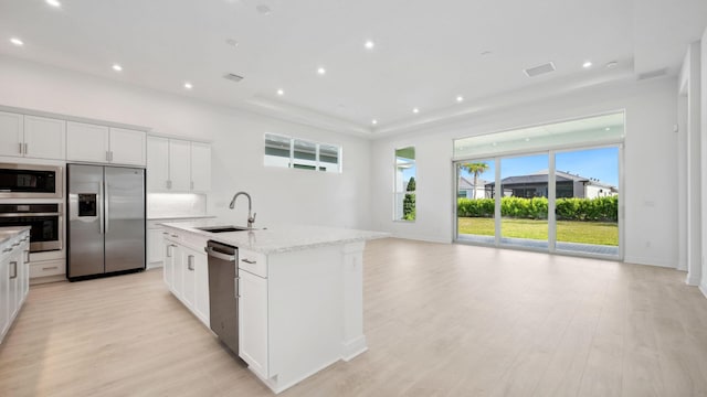 9143 SW Esule Way, Port Saint Lucie, FL 34987 - kitchen featuring appliances with stainless steel finishes, a sink, light wood-style floors, a center island with sink, and white cabinetry