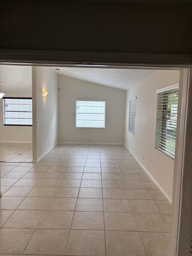 3962 Dafilee Cir, West Palm Beach, FL 33417 - empty room with light tile patterned flooring, vaulted ceiling, healthy amount of natural light, and baseboards