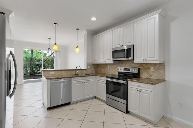 kitchen with appliances with stainless steel finishes, a sink, backsplash, white cabinets, and crown molding