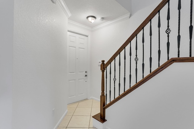 entryway with crown molding, light tile patterned floors, stairs, baseboards, and a textured ceiling