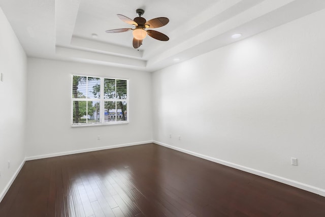 unfurnished room with ceiling fan, dark wood-style flooring, a tray ceiling, baseboards, and recessed lighting