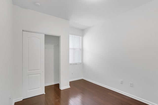 unfurnished bedroom with wood finished floors, a closet, and baseboards