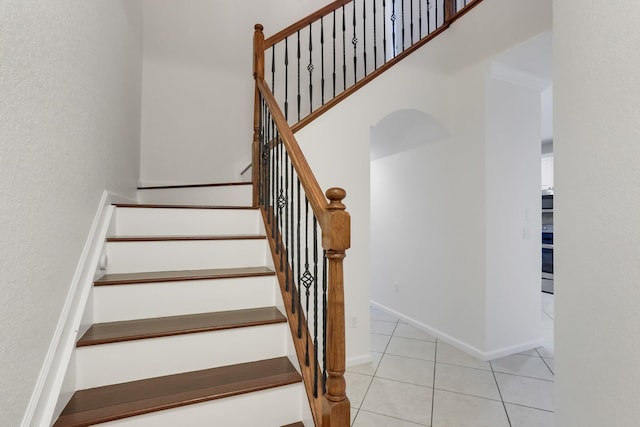 stairs with tile patterned floors and a textured wall