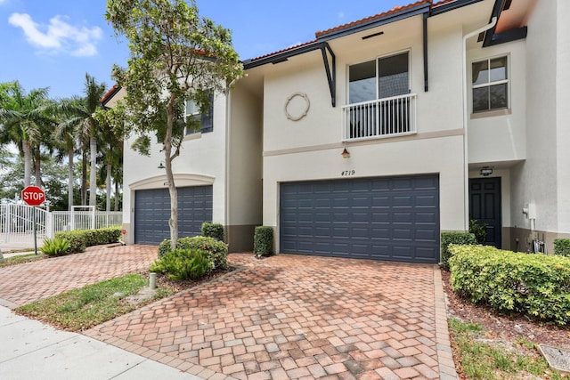 townhome / multi-family property with stucco siding, a garage, fence, and decorative driveway
