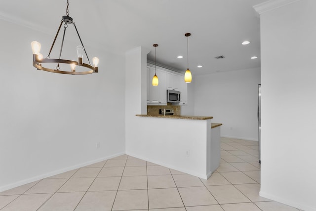 kitchen with stainless steel microwave, a chandelier, recessed lighting, white cabinets, and crown molding