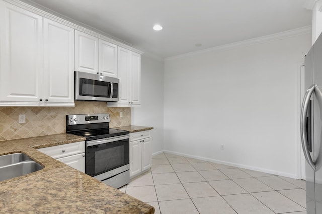 kitchen featuring stainless steel appliances, backsplash, white cabinetry, crown molding, and baseboards