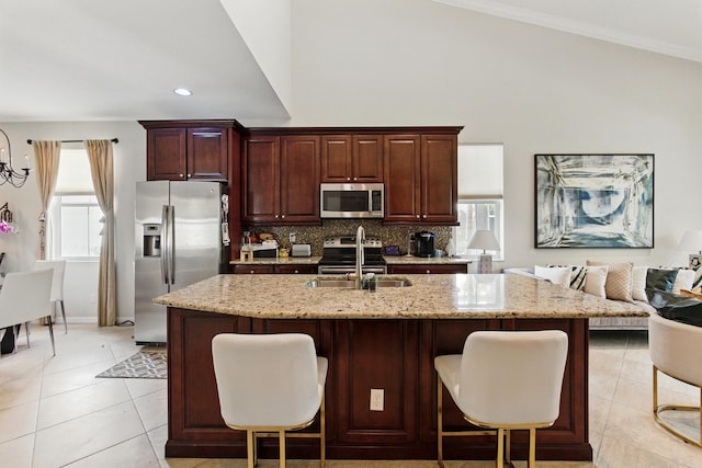 4635 Mediterranean Cir, Palm Beach Gardens, FL 33418 - kitchen featuring appliances with stainless steel finishes, a sink, light stone countertops, decorative backsplash, and a breakfast bar area
