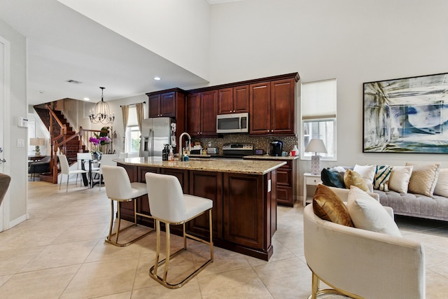 4635 Mediterranean Cir, Palm Beach Gardens, FL 33418 - kitchen with stainless steel appliances, a chandelier, tasteful backsplash, a breakfast bar area, and an island with sink