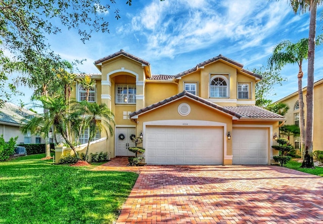 mediterranean / spanish-style house featuring decorative driveway, a tile roof, a front lawn, and stucco siding