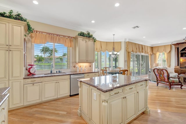 kitchen with a sink, cream cabinets, dishwasher, open floor plan, and a chandelier