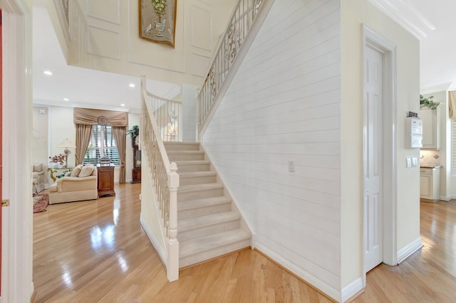 stairway featuring wood finished floors, baseboards, recessed lighting, and crown molding