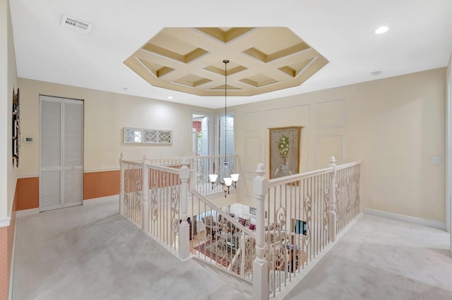 hallway featuring coffered ceiling, an upstairs landing, carpet, beamed ceiling, and baseboards