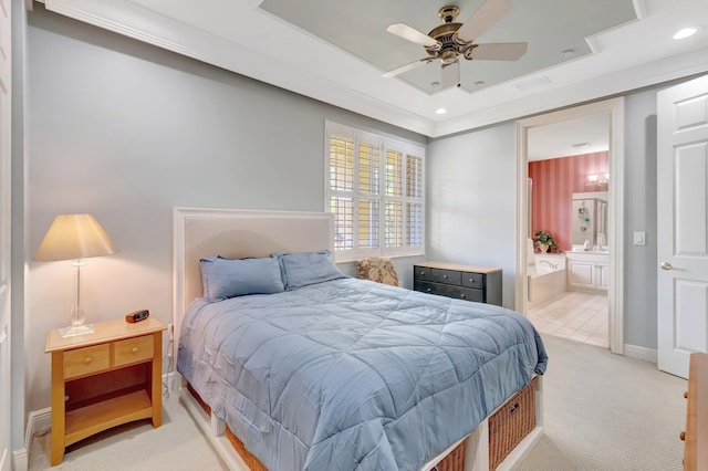bedroom with light colored carpet, a raised ceiling, ensuite bathroom, recessed lighting, and baseboards