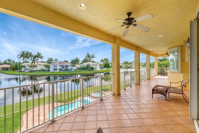 balcony with ceiling fan, a water view, view of pool area, a residential view, and a pool with connected hot tub