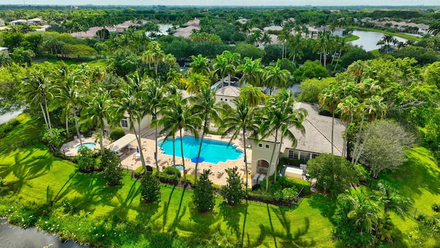 aerial view of a pool area, a large body of water, and a tree filled landscape