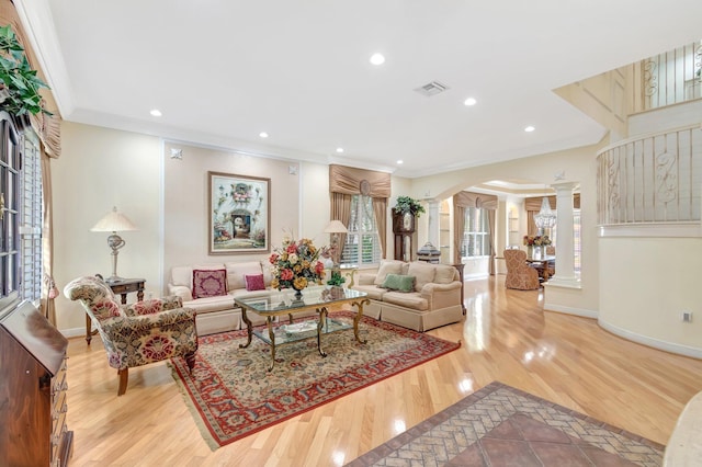 living room featuring decorative columns, arched walkways, wood finished floors, crown molding, and recessed lighting