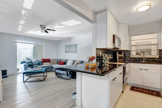 1124 NW 13th St Unit 208, Boca Raton, FL 33486 - kitchen featuring stainless steel microwave, dark countertops, open floor plan, decorative backsplash, and white cabinets