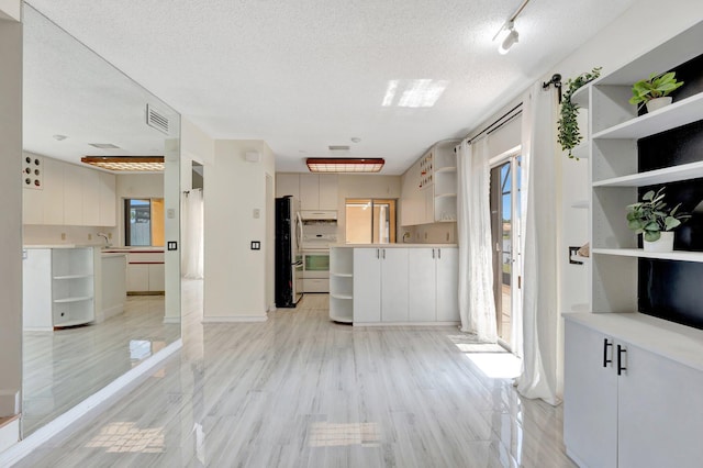 1388 Garden Rd, Weston, FL 33326 - kitchen with open shelves, freestanding refrigerator, healthy amount of natural light, range, and a textured ceiling