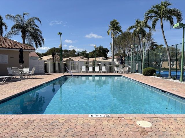 community pool with fence and a patio area