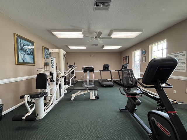 exercise room with a ceiling fan, a textured ceiling, and baseboards