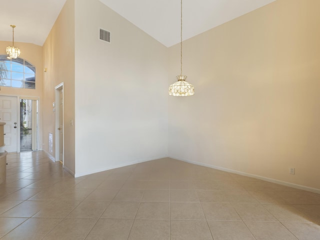 spare room featuring a chandelier, light tile patterned floors, high vaulted ceiling, and baseboards