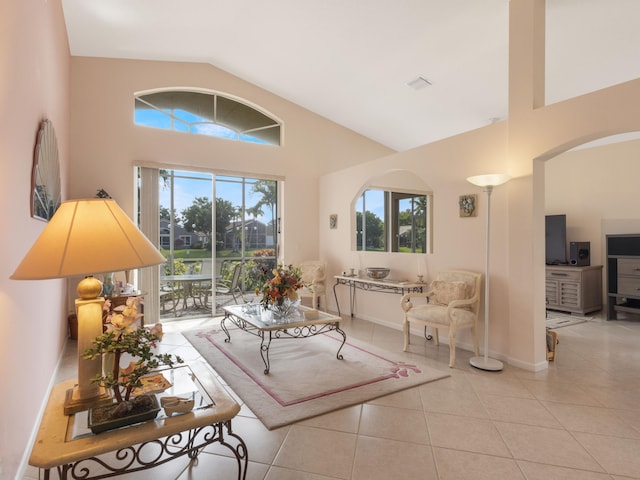 living room featuring high vaulted ceiling, light tile patterned flooring, arched walkways, and baseboards