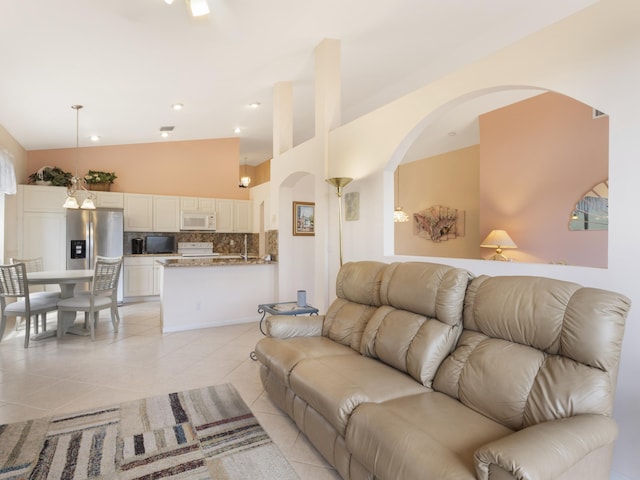 living room featuring light tile patterned floors, arched walkways, and vaulted ceiling