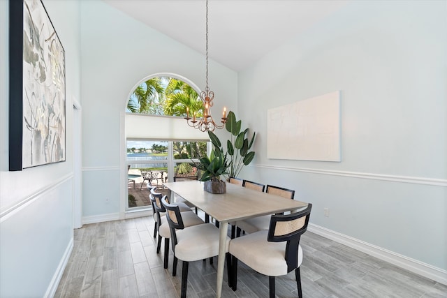 dining room featuring light wood-style floors, a chandelier, baseboards, and high vaulted ceiling