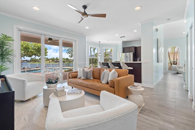 living room with a ceiling fan, crown molding, baseboards, recessed lighting, and light wood-style flooring
