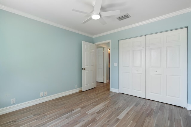 unfurnished bedroom featuring light wood finished floors, crown molding, a closet, baseboards, and a ceiling fan