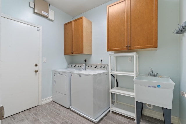 clothes washing area featuring cabinet space, washer and dryer, light wood-style floors, and baseboards