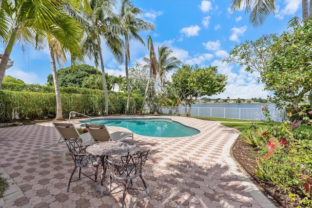 view of pool with fence, a water view, and a patio area