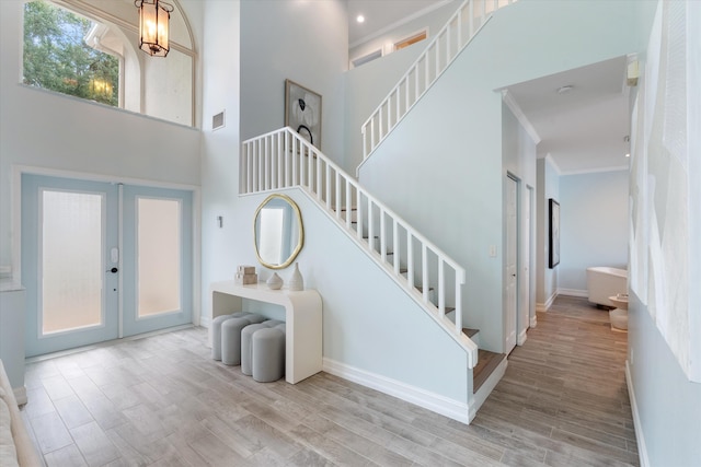 staircase featuring crown molding, wood finished floors, french doors, baseboards, and a chandelier