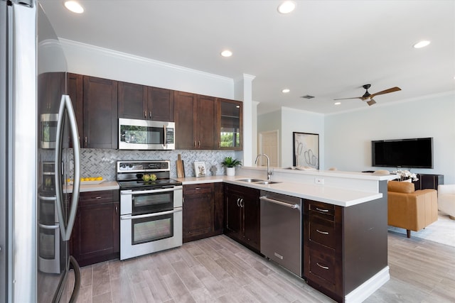 kitchen featuring stainless steel appliances, a sink, open floor plan, a peninsula, and tasteful backsplash