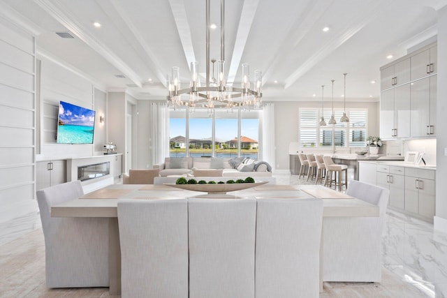 living room featuring recessed lighting, a chandelier, healthy amount of natural light, a glass covered fireplace, and ornamental molding