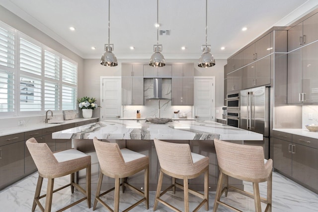 kitchen featuring stainless steel appliances, gray cabinets, wall chimney range hood, a spacious island, and crown molding