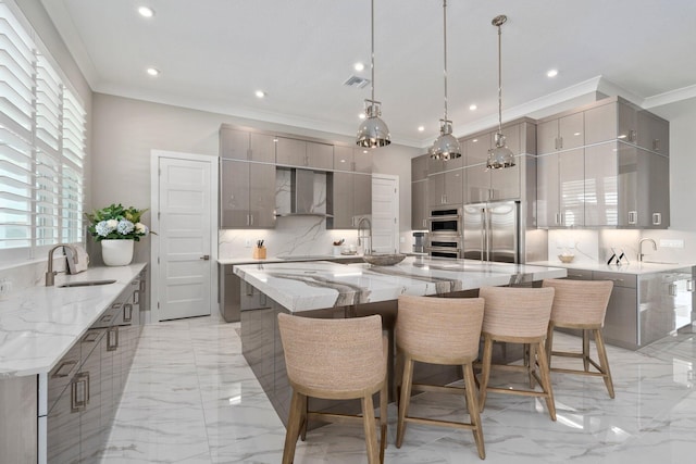 kitchen featuring gray cabinetry, built in refrigerator, a sink, wall chimney exhaust hood, and ornamental molding
